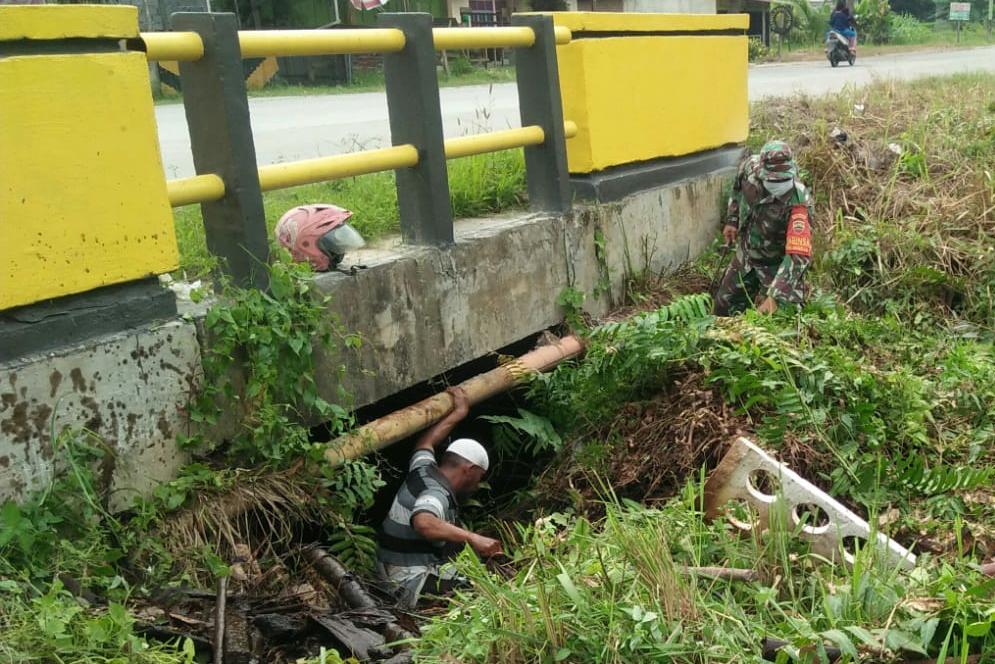 Bersama Warga dan Perangkat Kelurahan, Serda Cercakatno Bersihkan Aliran Sungai